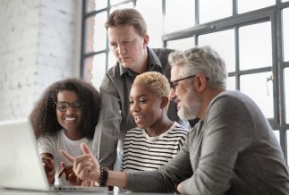 A diverse team of colleagues sit together looking at a computer screen.