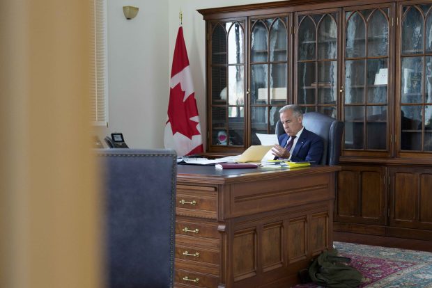 Prime Minister Mark Carney prepares for a meeting with chief executive officers of the automotive industry in his office in July 2025.