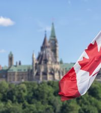 A photo of the Canadian flag with Parliament Hill,in the background