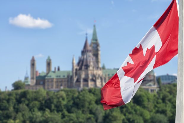 A photo of the Canadian flag with Parliament Hill,in the background