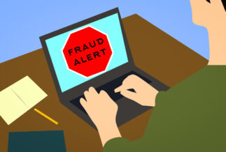 Illustration of a man sitting at a computer with a fraud alert on the screen.