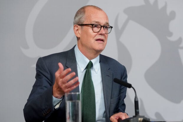 Patrick Vallance, the UK minister of state for science, research and innovation gives a speech at a lectern against a grey background.